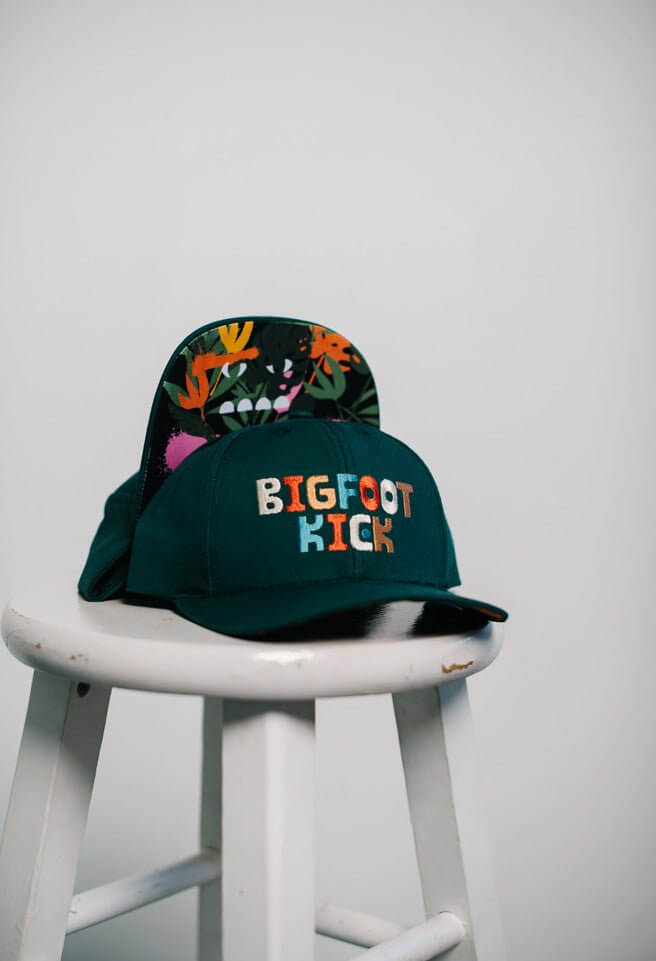 Hidden Bigfoot Hat displayed on a stool showcasing its unique Bigfoot-themed design.